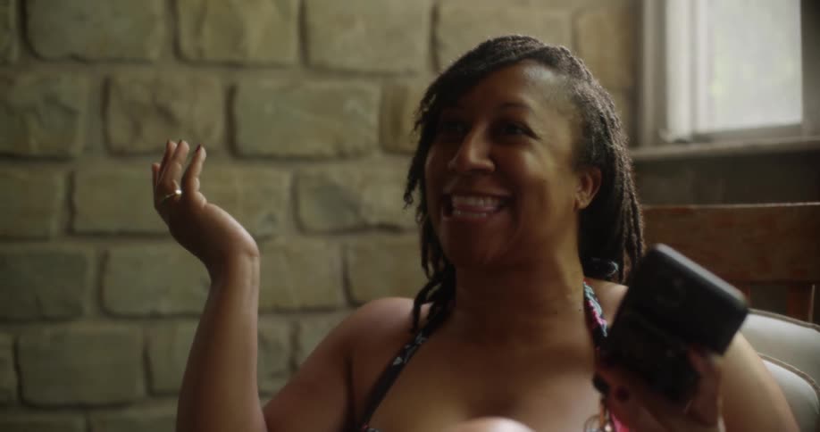Woman looking at her phone before laughing and talking to someone else