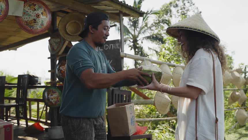 A woman buying coconut water from a roadside stall in the countryside