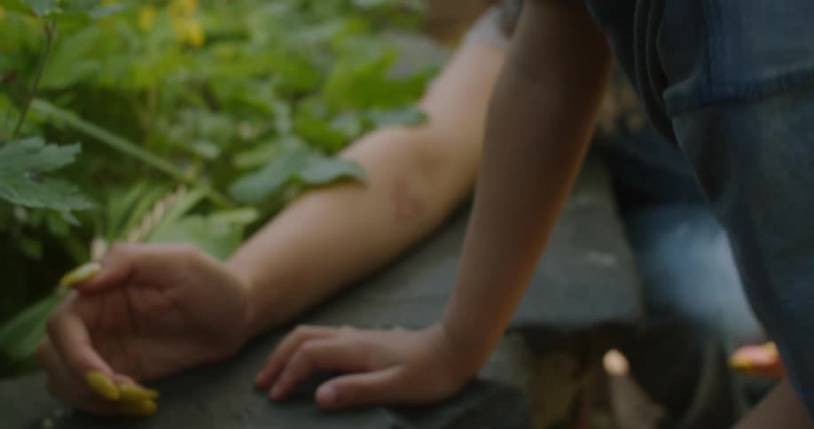 A happy little boy is playing with some insects as his mother encourages his learning