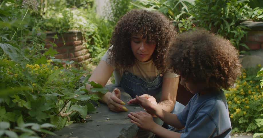 A mother shows her son a bug in a garden