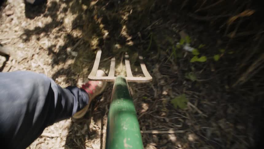 Point of view of a person using a pitchfork in a garden