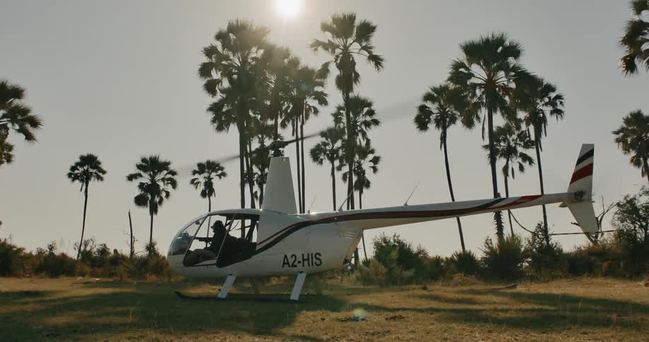 Person inside a helicopter with the propellers moving while in a natural field