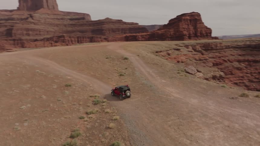 Red sports car traveling through a natural environment surrounded by canyons