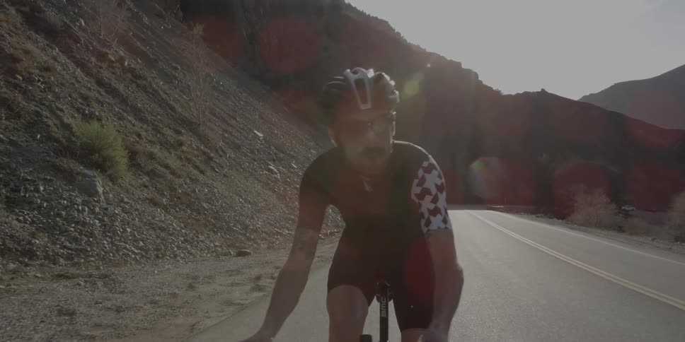 Cyclist riding up a small incline next to a  highway  with no traffic