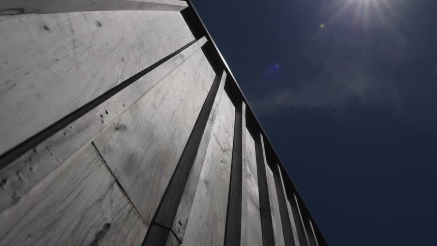 Exterior architecture of a wooden property against a blue sky with sunlight