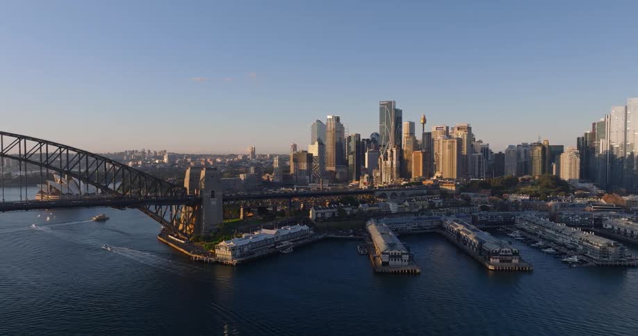 A coastal cityscape with high rise buildings near the waters edge and sailboats scattered in the harbor