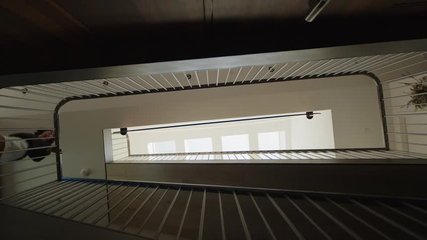 View upwards from the interior of a house with stairs that give access to the upper floors and a person going up