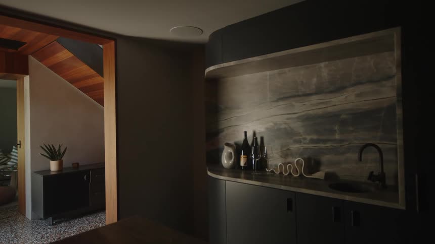 A modern kitchen with darktoned cabinetry and a marble backsplash