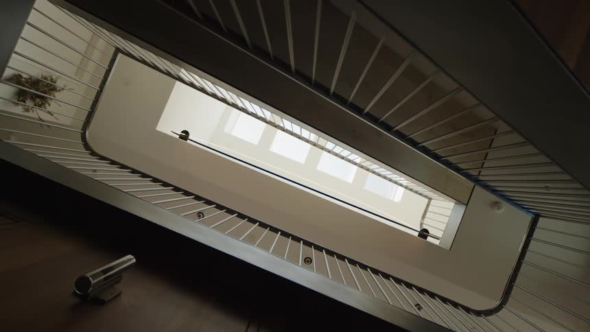 Camera points up looking at a staircase with a skylight on the ceiling