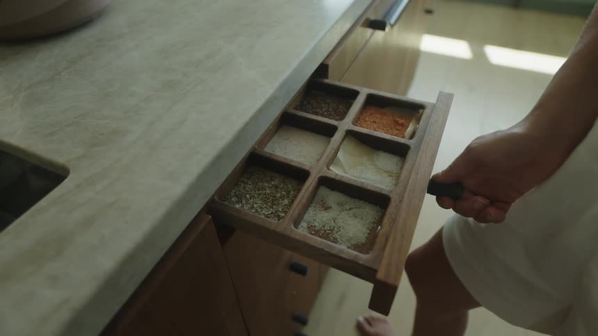 Womans hand opening a drawer with spices in the kitchen