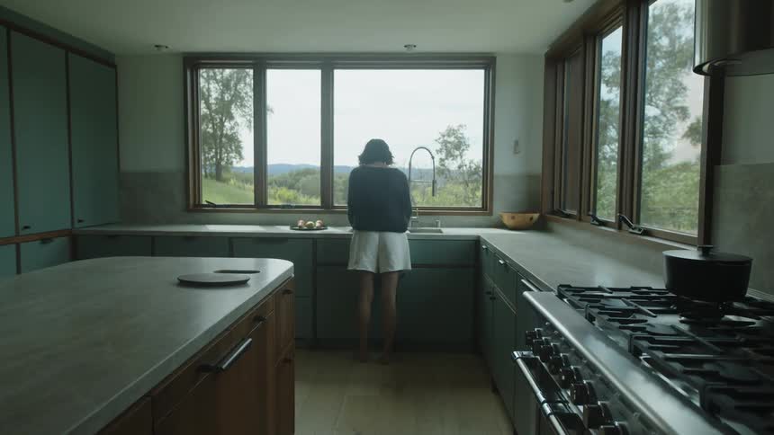 Woman at the sink then placing a plate of grapes on a marble countertop