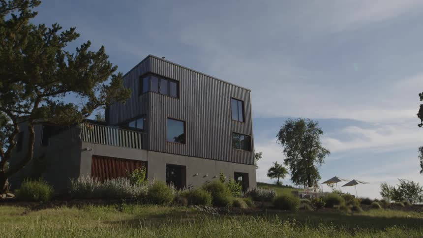 Twostory house in a natural setting against a partly cloudy sky