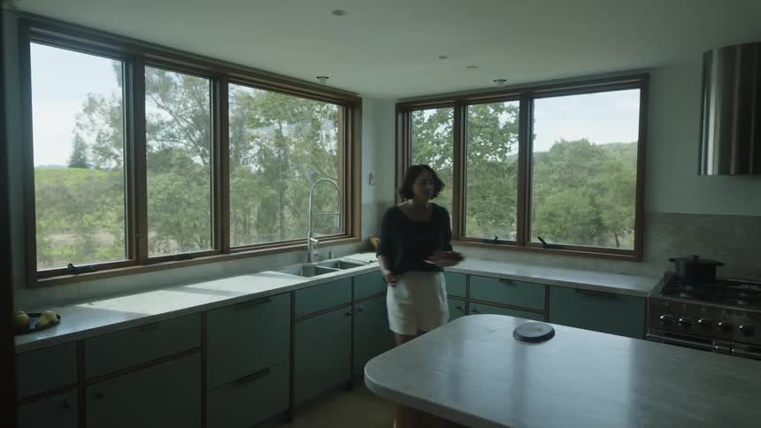 Woman washing a plate of grapes in the sink and placing it on a table in the kitchen