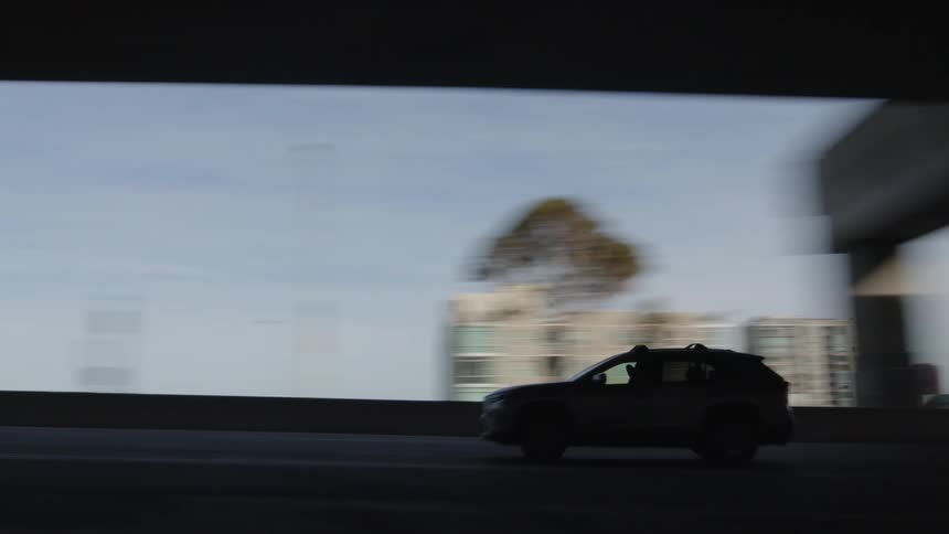Silhouette of a car passing on an overpass and in the background the buildings of a city
