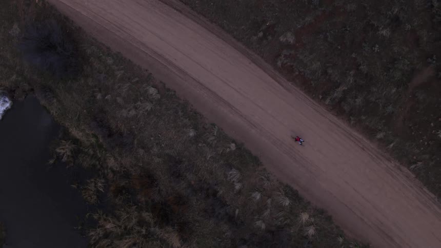A person is riding their bike down below on a dirt trail
