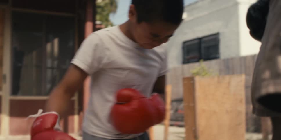Boy training boxing with an adult gets hit and falls to his knees in pain