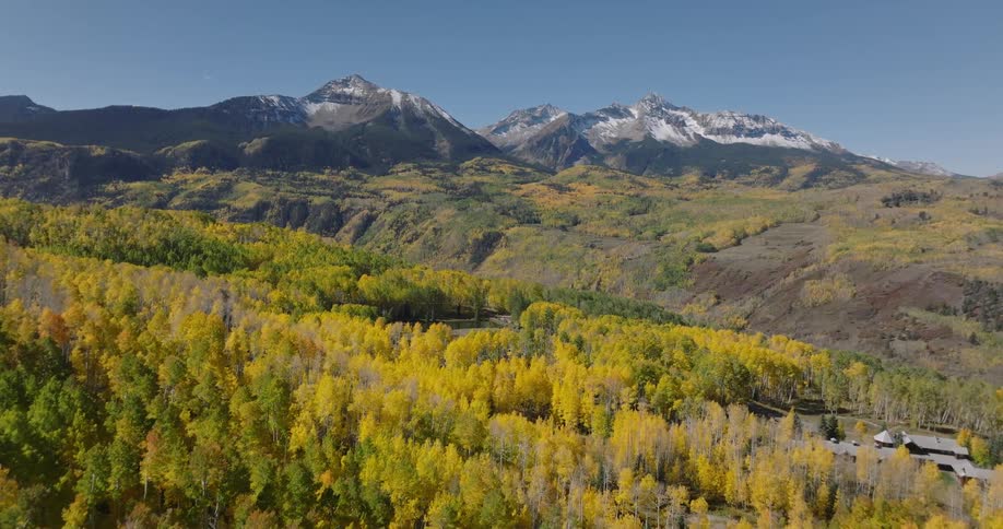 Aerial scenery of forested mountains with snowcapped peaks on the horizon