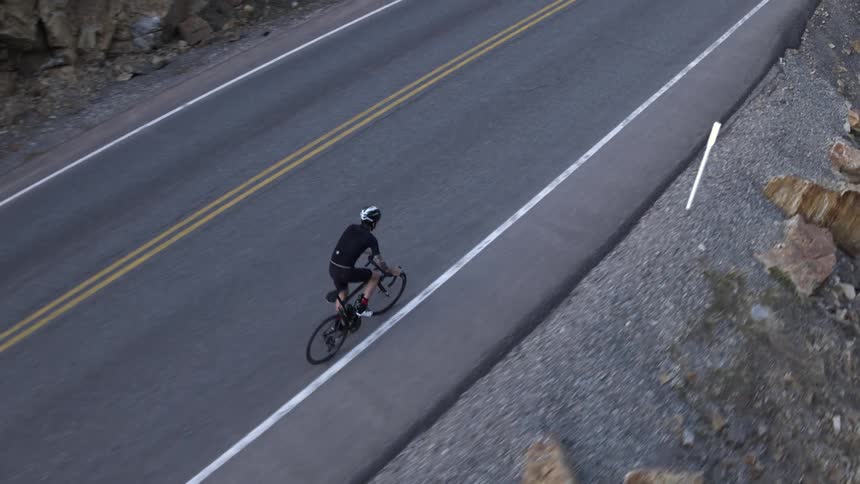 A man is cycling on the side of the road,