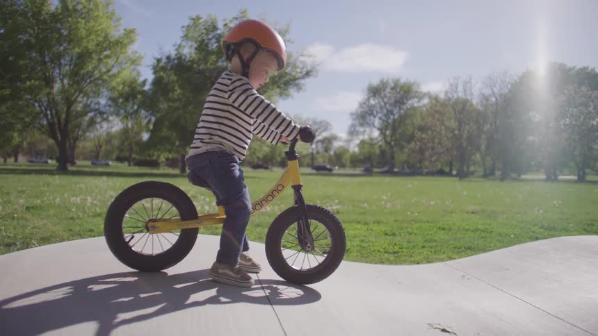 Small blond boy learning to ride a bike without a support