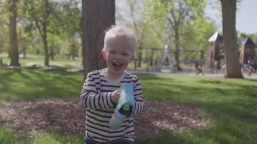 Little blond boy running holding a soap water gun