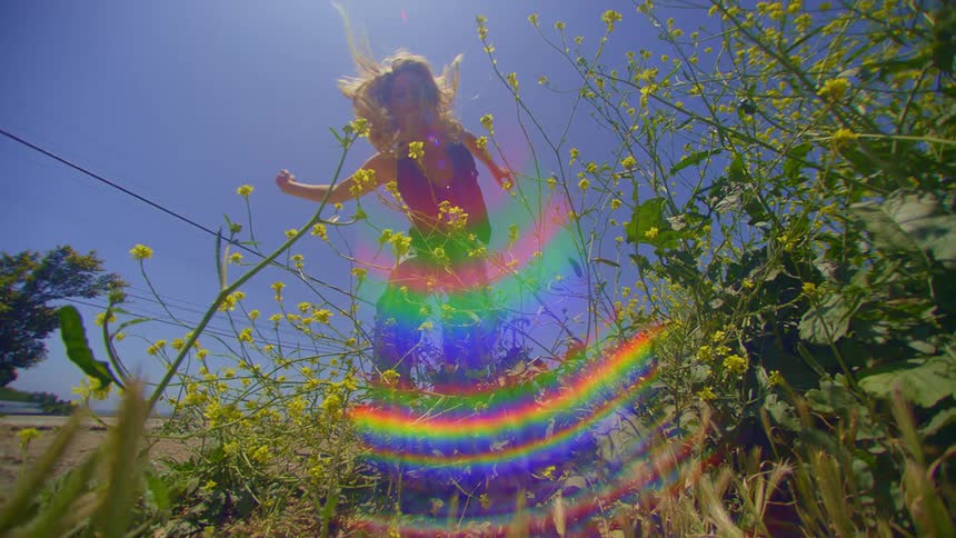 Reflection of a rainbow and a woman dancing next to flowers