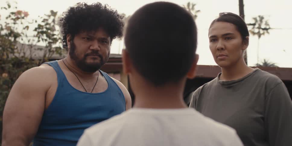 Two parents stand in front of a child with his back to the camera on a questioning and aggressive stance