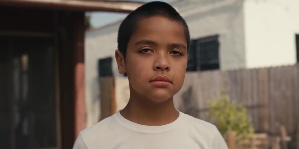 Close up of the face of a sad child crying in the front yard of a house