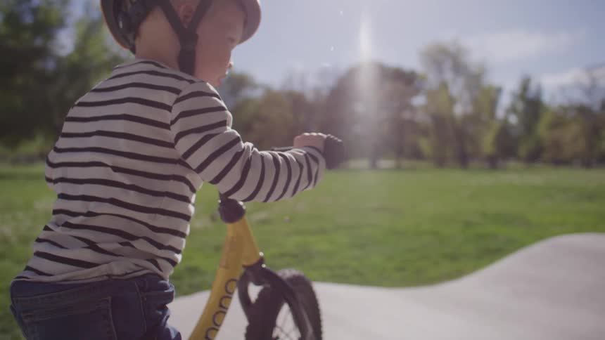 Small boy on a bicycle with helmet riding in a park