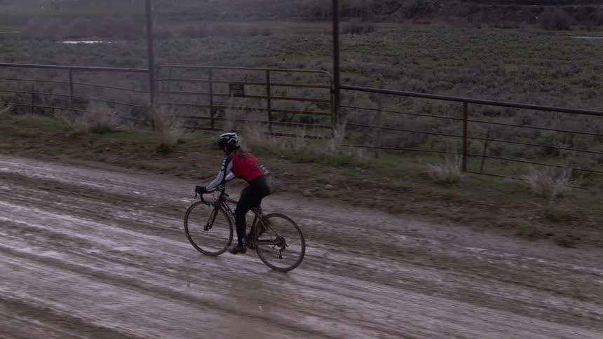 A woman cycling down a rural dirt road