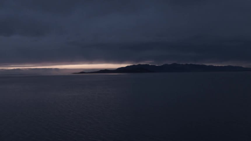 Moving across the water at sunset with heavy clouds above