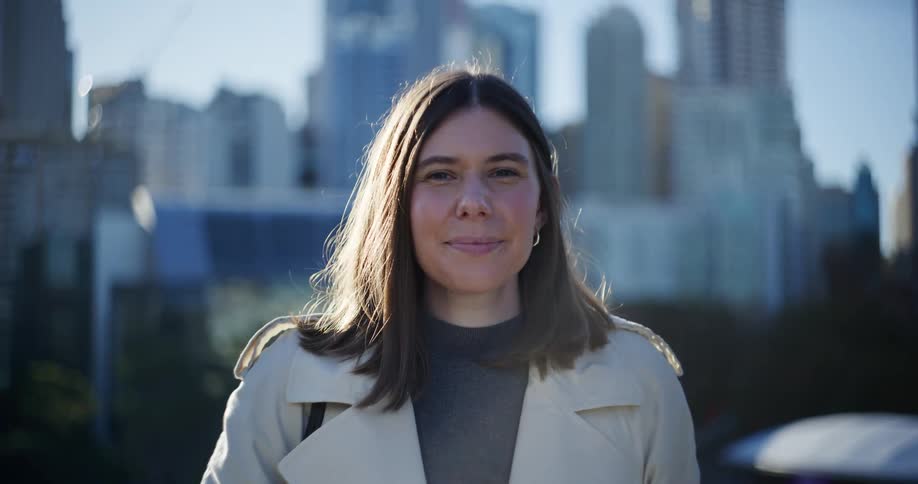 A woman smiles looking forward with a cityscape in the background
