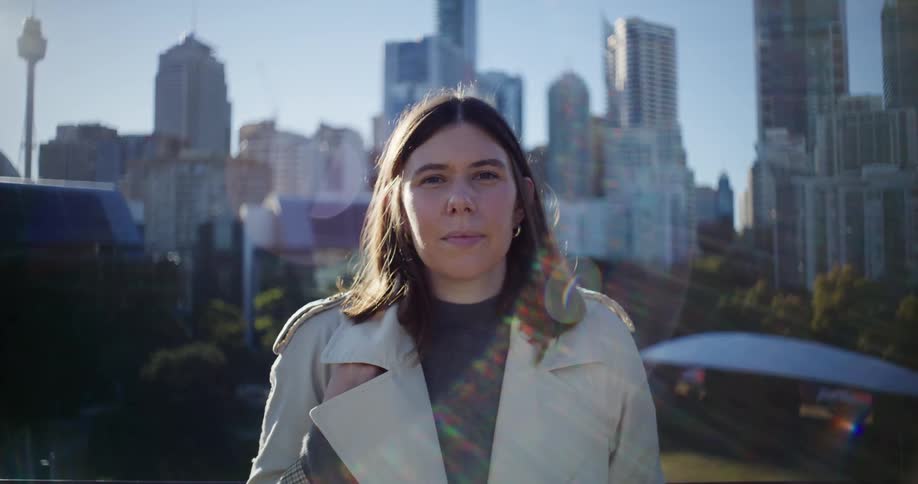 Woman stands in a park near the downtown skyscrapers on a sunny day