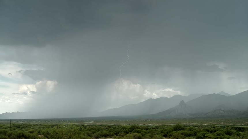 Lightning stretches to the ground in front of the mountains