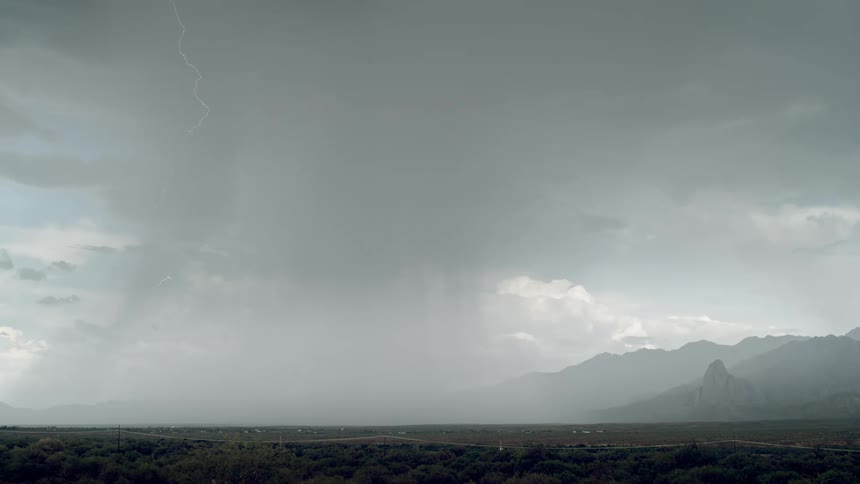 Mountainous landscape on a cloudy day with bursts of lightning