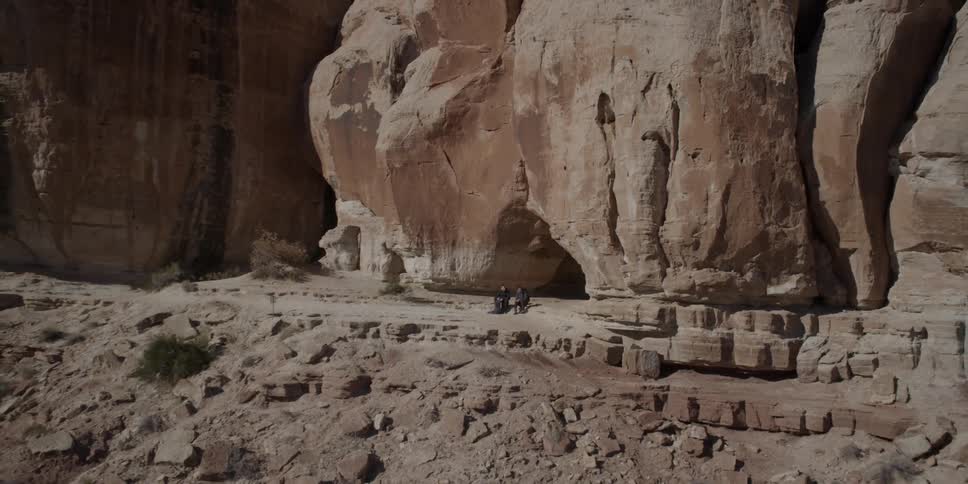 Two hikers rest outside a cavern