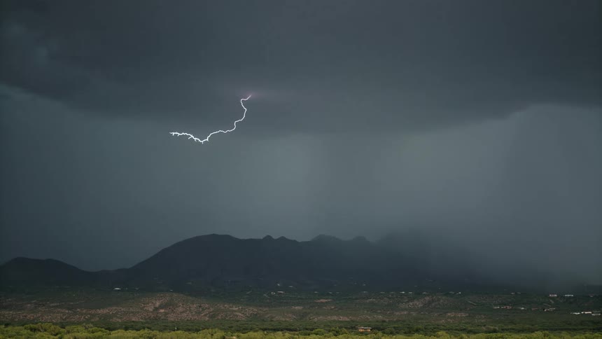 Storm with rain and lightning above mountains