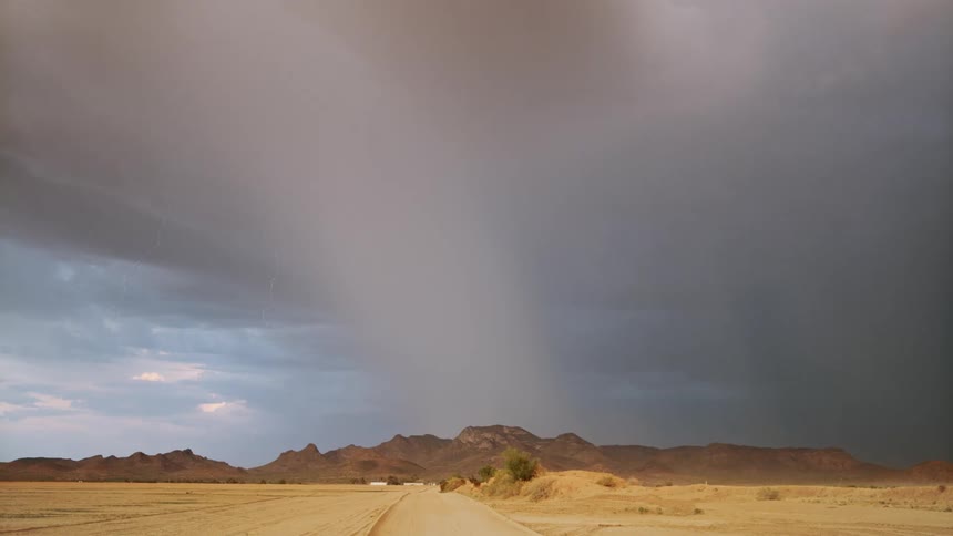 A lightning storm strikes above a plain and a mountain range