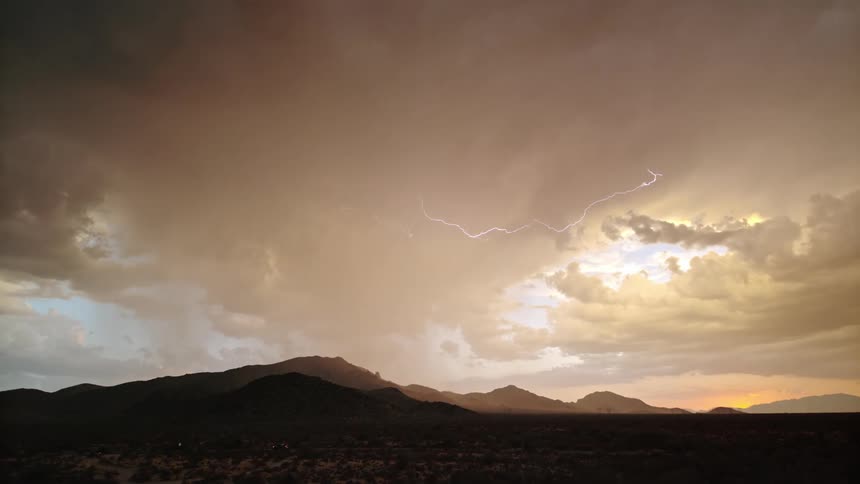 Storm with lightning in a late afternoon sky above mountains