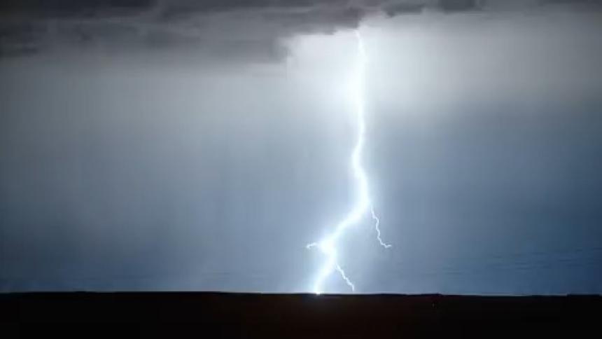 A jagged lightning bolt during a storm against a dark sky shooting downwards into the ground