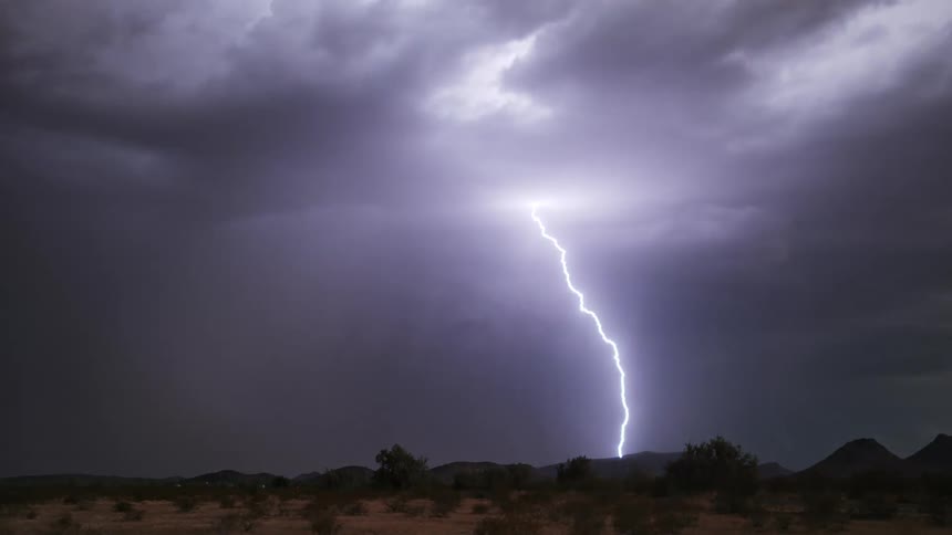 Desert landscape with mountains in the background on a day with storm and thunder