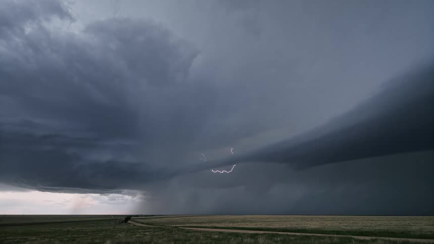 A dramatic thunderstorm with lightning strikes over the plains in daylight