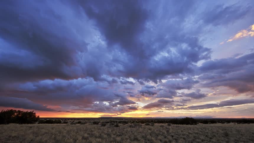 A breathtaking sunset with vibrant red and purple clouds over a vast open landscape