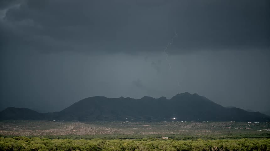 Lightning bolts strike the ground below a dark and stormy sky