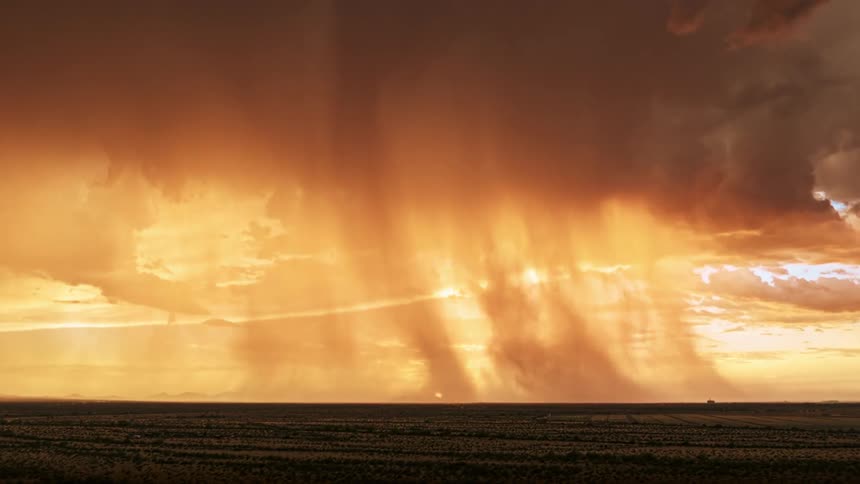Storm clouds rapidly move forming a tornado as the sun sets