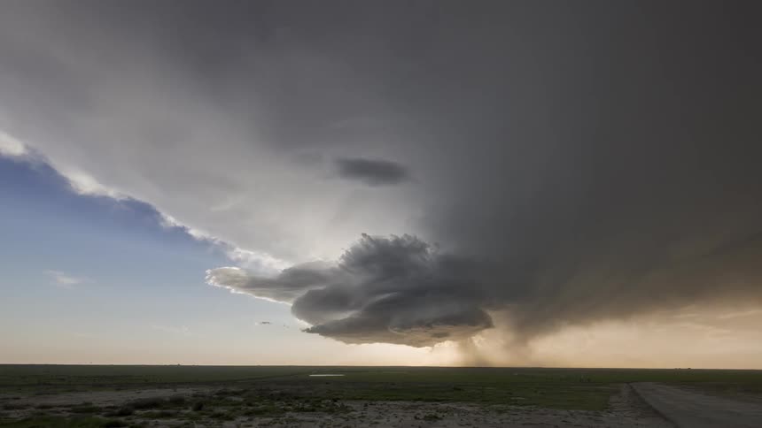 A time lapse of dark sprawling storm clouds rolling over a vast landscape
