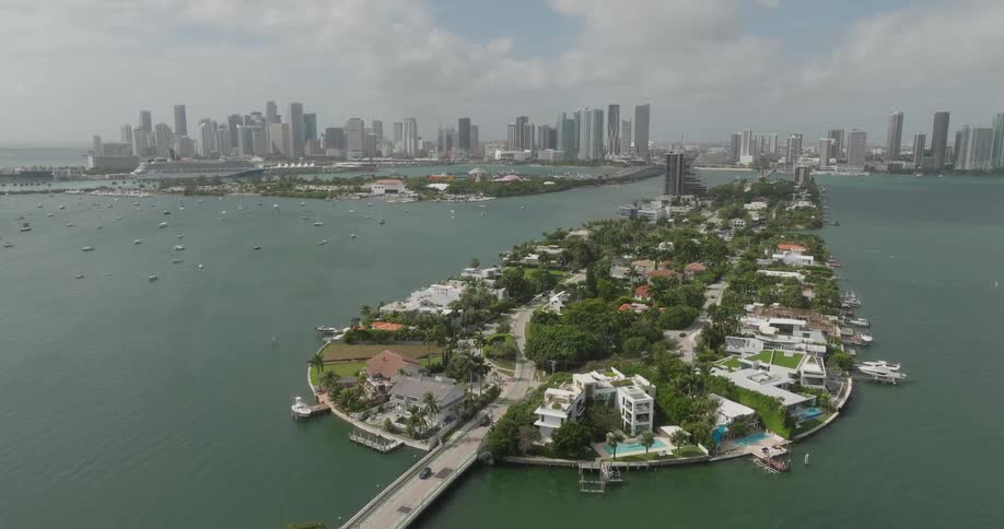 An aerial view reveals a coastal cityscape with highrise buildings in the background
