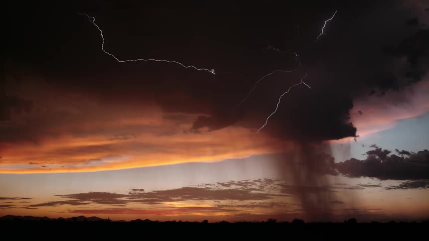 A lightning storm strikes above a grassland at dusk