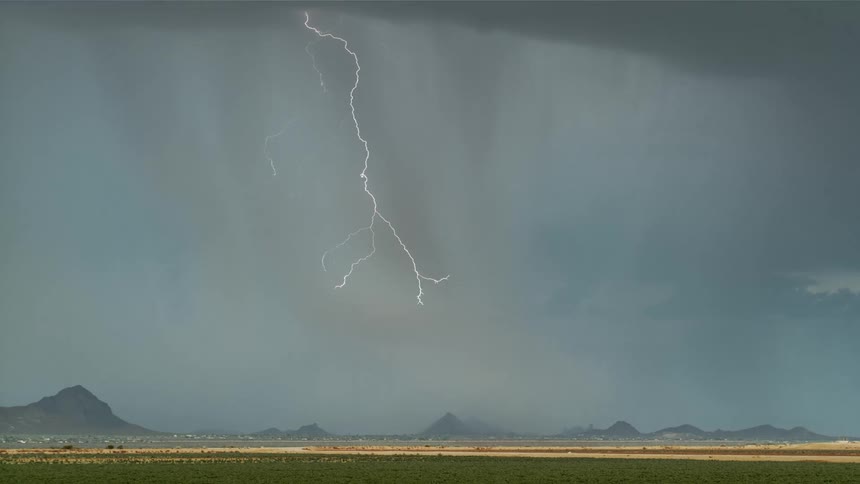 A dramatic thunderstorm with lightning strikes the plains in daylight