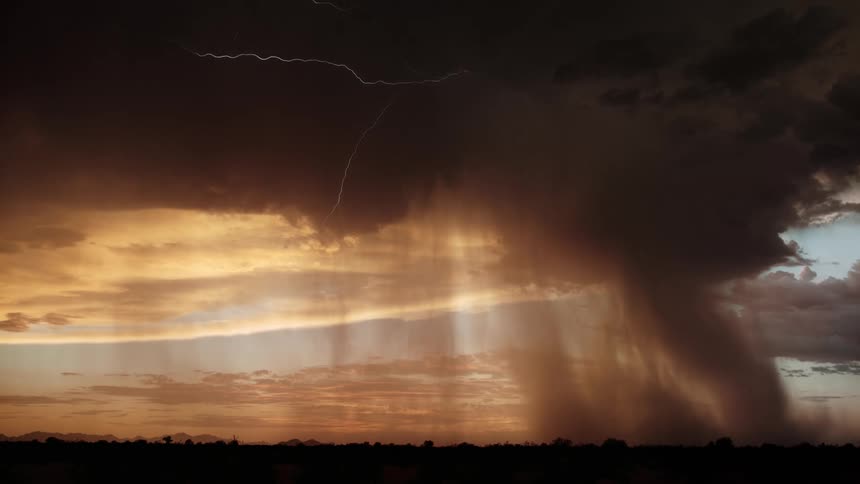 Lightning streaks and flashes from very dark clouds over a field