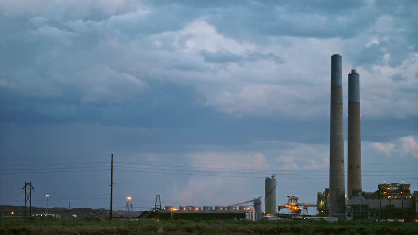 Smokestacks in an industrial area in front of a lightning storm